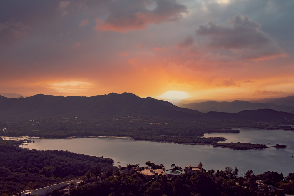 body of water near mountain during sunset