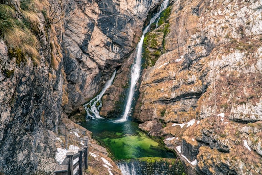 water falls between brown rocky mountain during daytime in Triglav National Park Slovenia