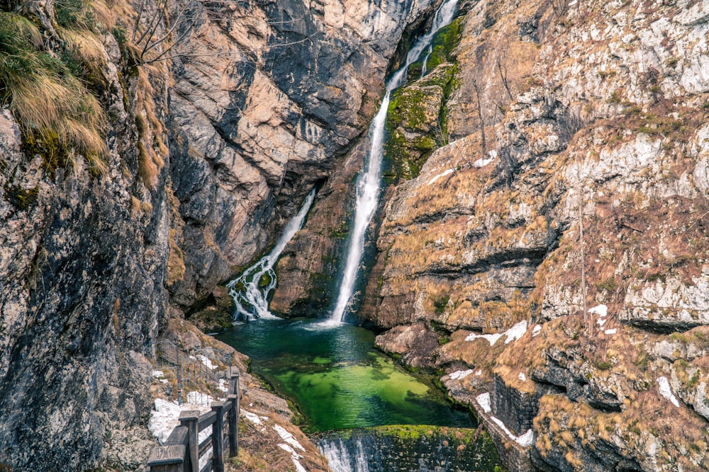 water falls between brown rocky mountain during daytime