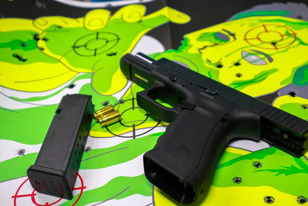 Pistola semiautomática negra sobre textil verde y blanco