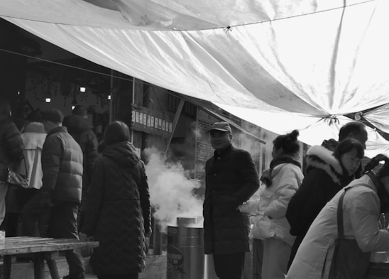 A candid black and white photo of a bustling street market captured on analog film.