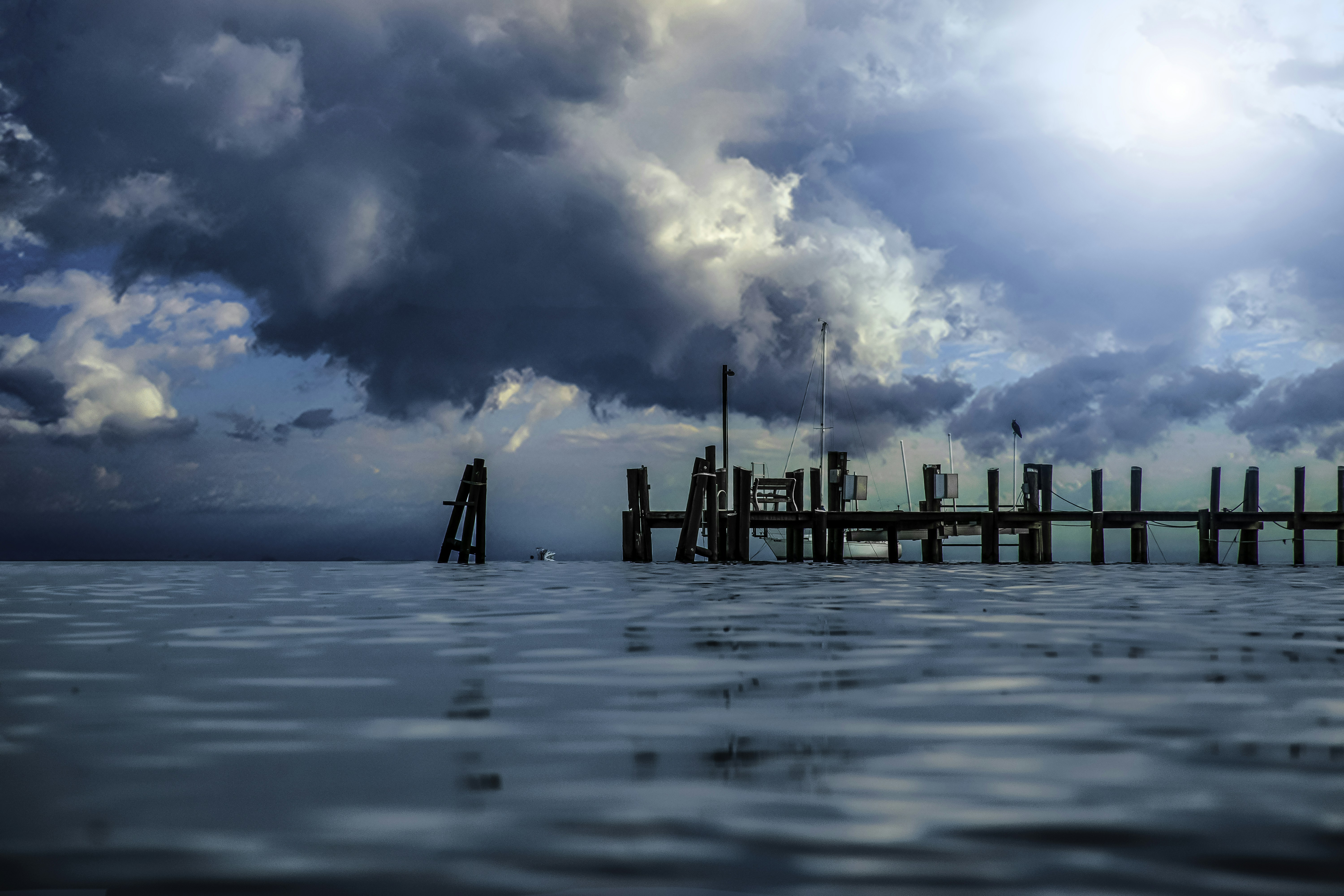 brown wooden dock on sea under blue sky and white clouds during daytime