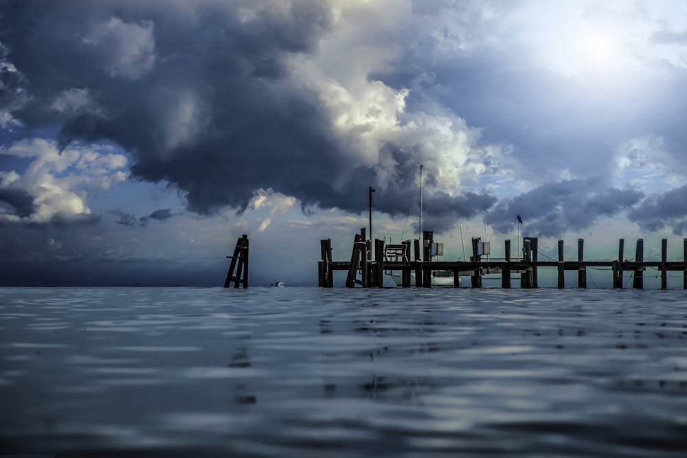 brown wooden dock on sea under blue sky and white clouds during daytime