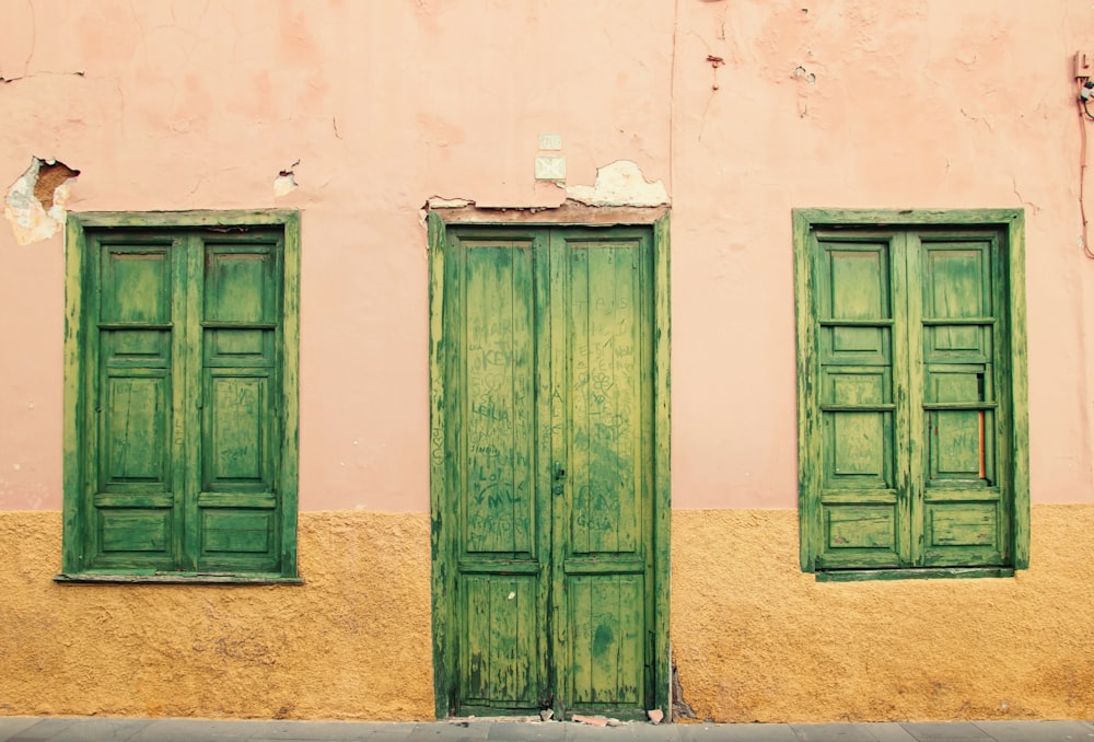 puerta de madera verde sobre pared de hormigón blanco