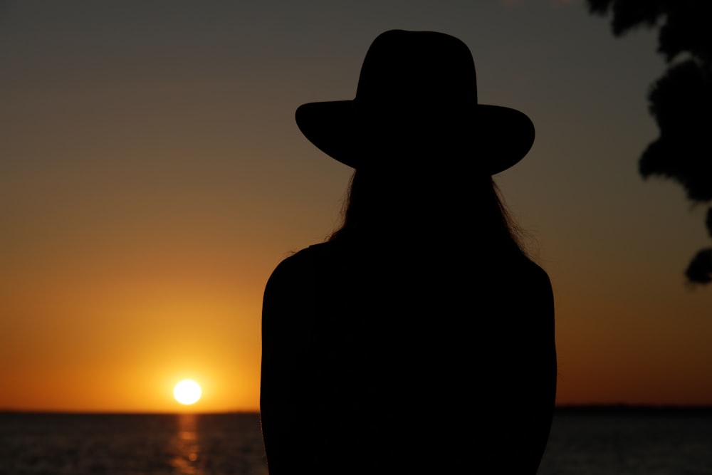 silhouette of woman wearing cowboy hat during sunset