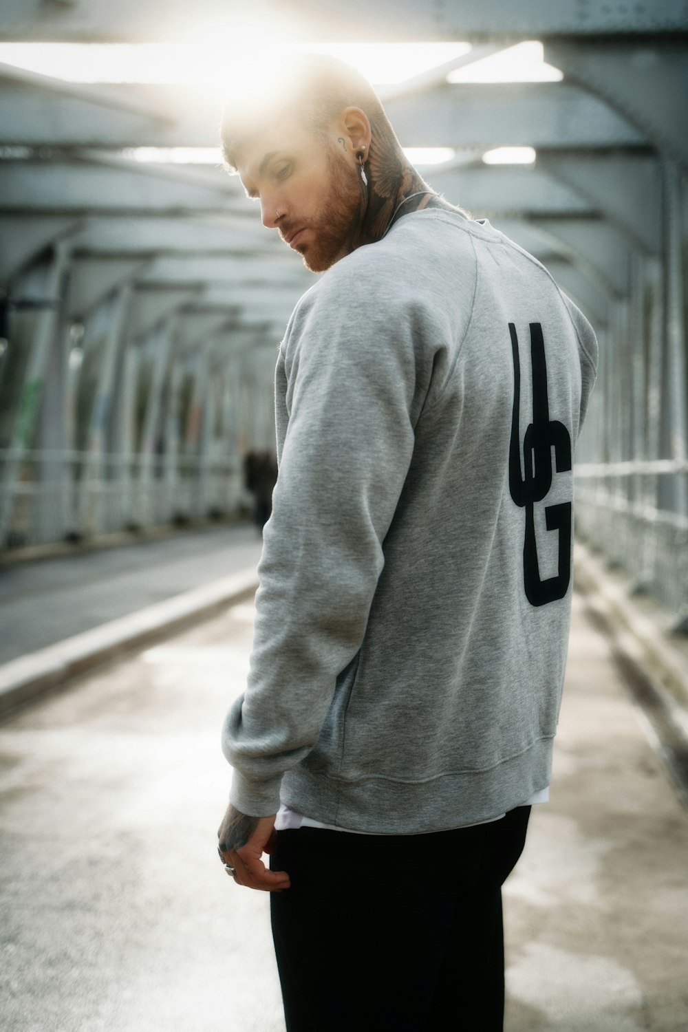 man in gray hoodie standing on road during daytime