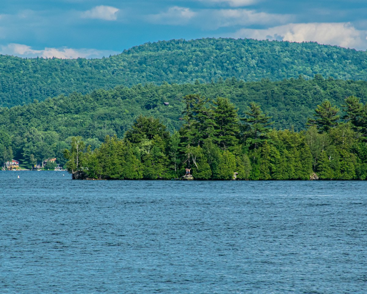 A forested island and mountains across open lake water