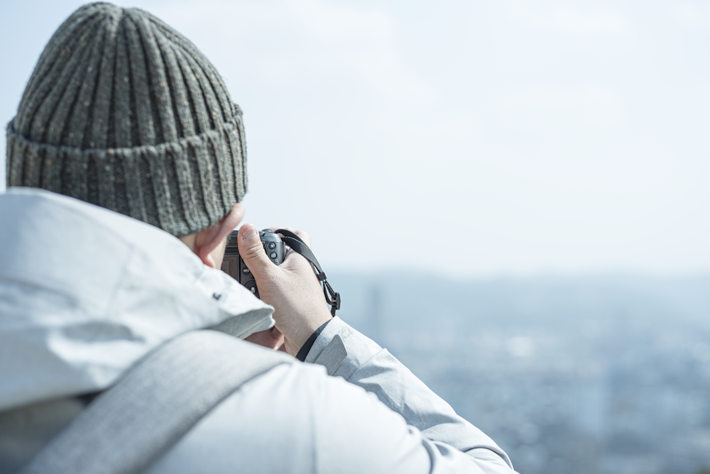 person in gray knit cap and white jacket holding black camera