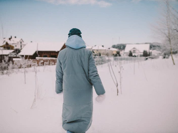 Person wearing a thick winter coat walking through a snowy city street.