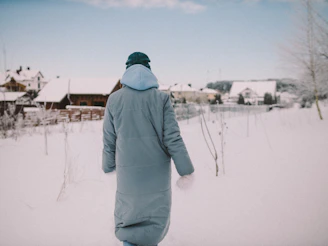 Person wearing a thick winter coat walking through a snowy city street.