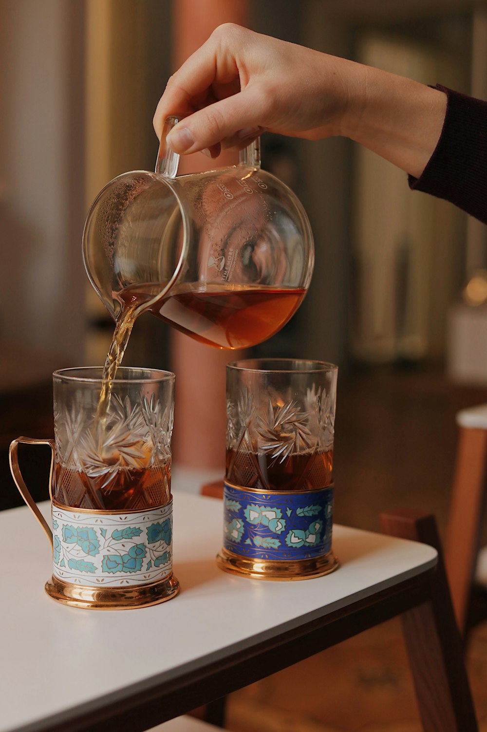 person pouring tea on clear glass mug