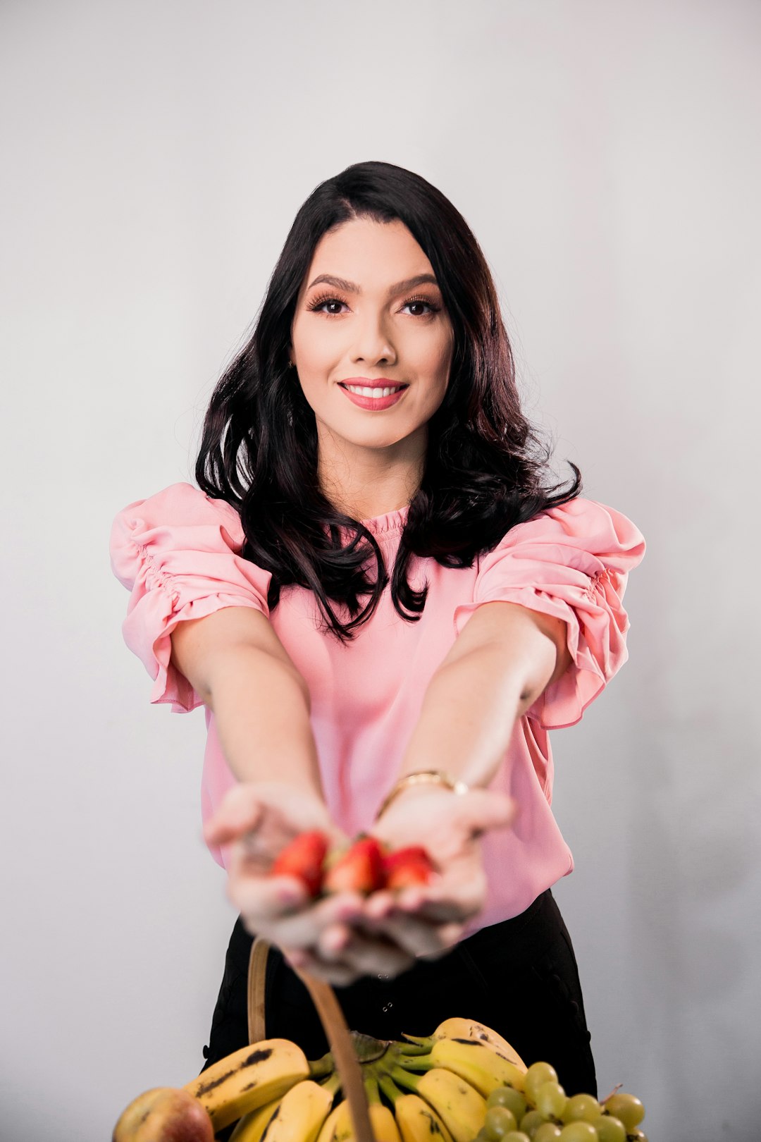 woman in pink long sleeve shirt holding red fruit