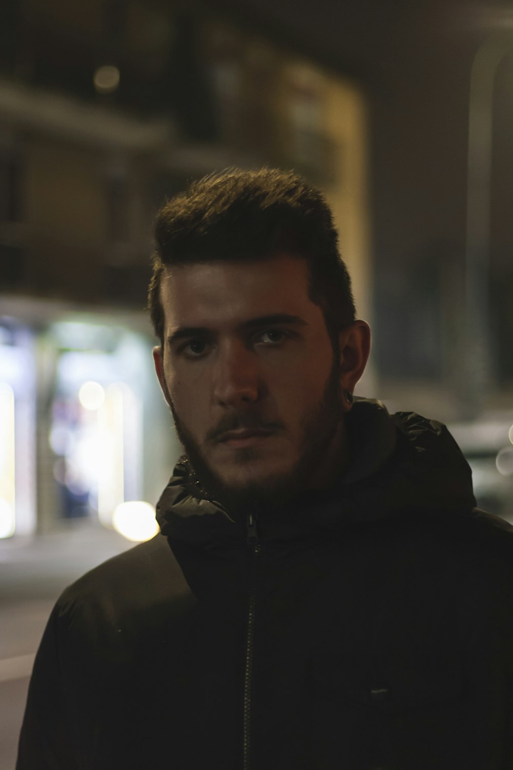 man in black hoodie standing near glass window