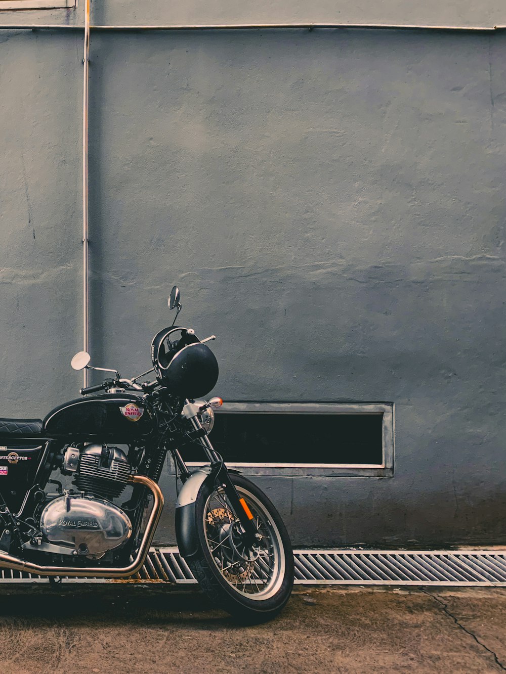 Motocicletta nera parcheggiata accanto al muro grigio