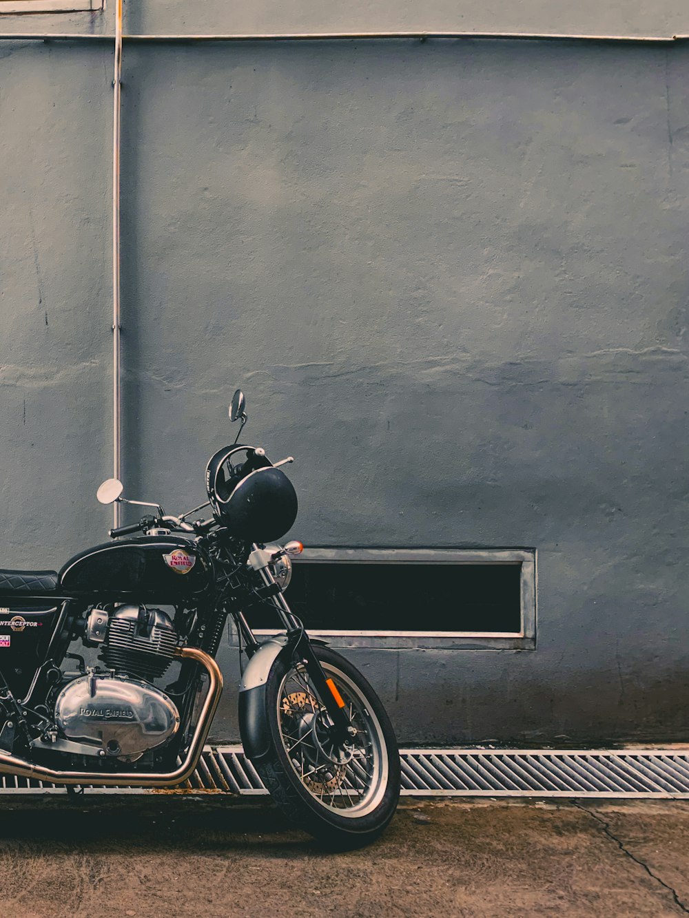 black motorcycle parked beside gray wall