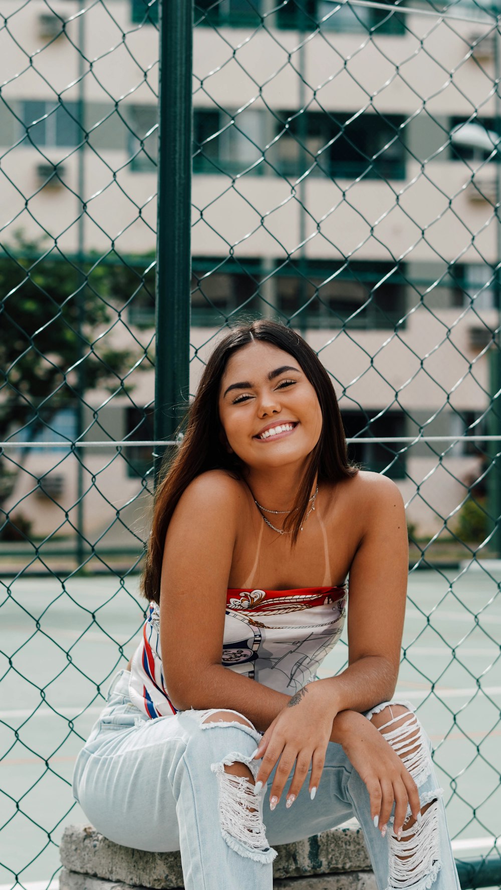 woman in red and white tube dress standing beside chain link fence