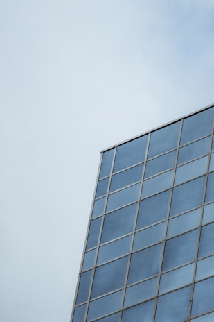 Close-up of a sleek glass curtain wall reflecting a bright blue sky.