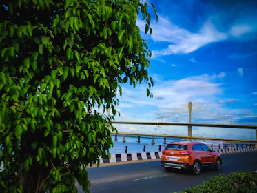 orange car on gray concrete road near bridge under blue sky during daytime