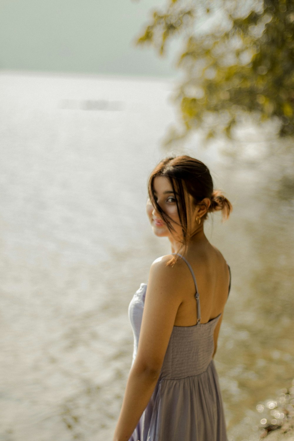 woman in white tank top standing near body of water during daytime