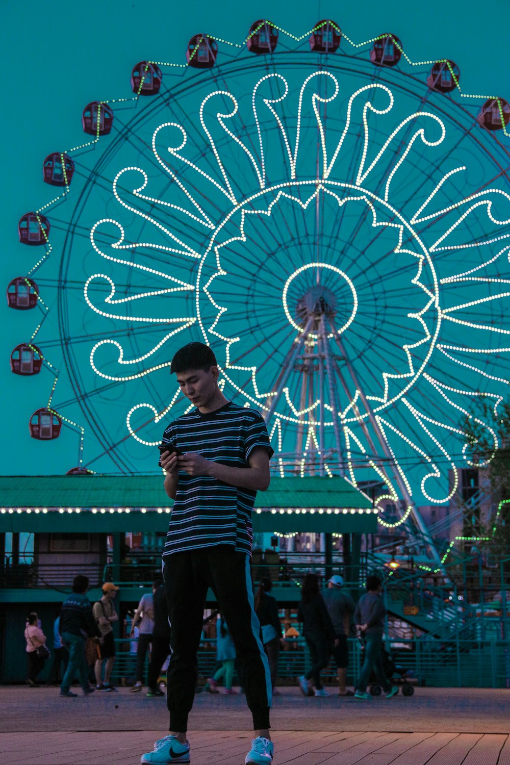 woman in red and white striped shirt standing near ferris wheel during nighttime