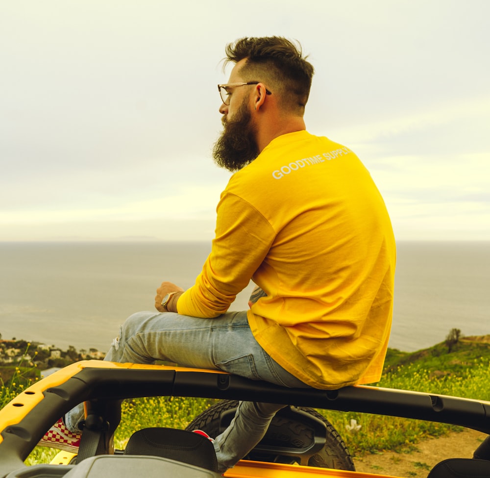 man in yellow long sleeve shirt sitting on black metal railings during daytime