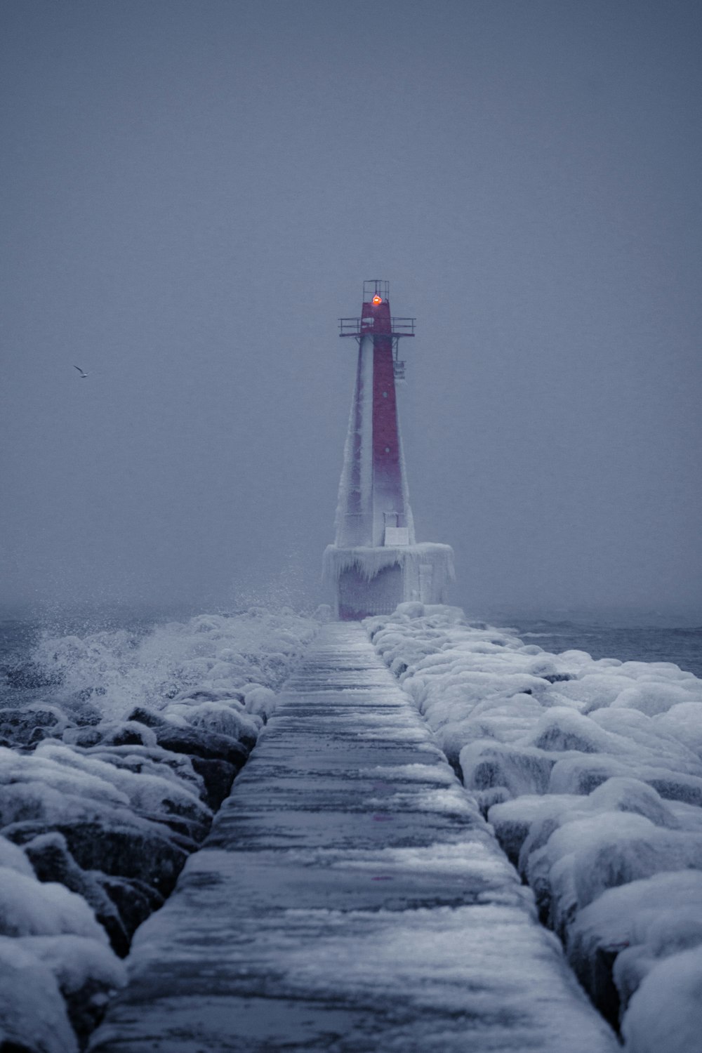 white and red lighthouse on gray rocky shore during daytime