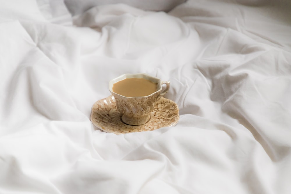 white ceramic mug on white textile