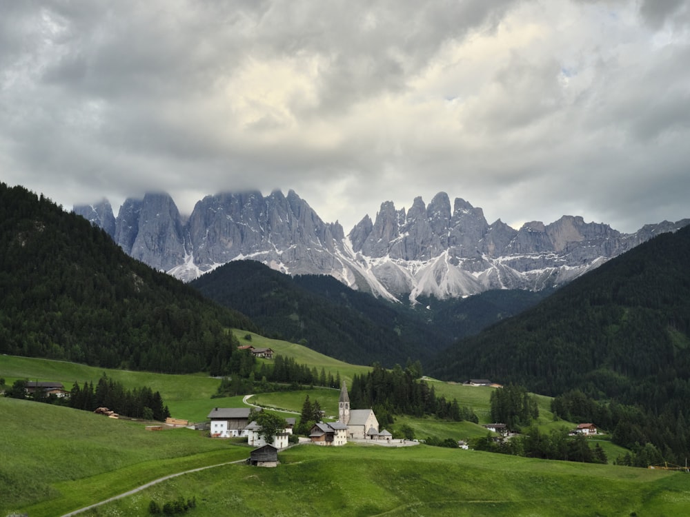 green grass field near mountains under white clouds during daytime