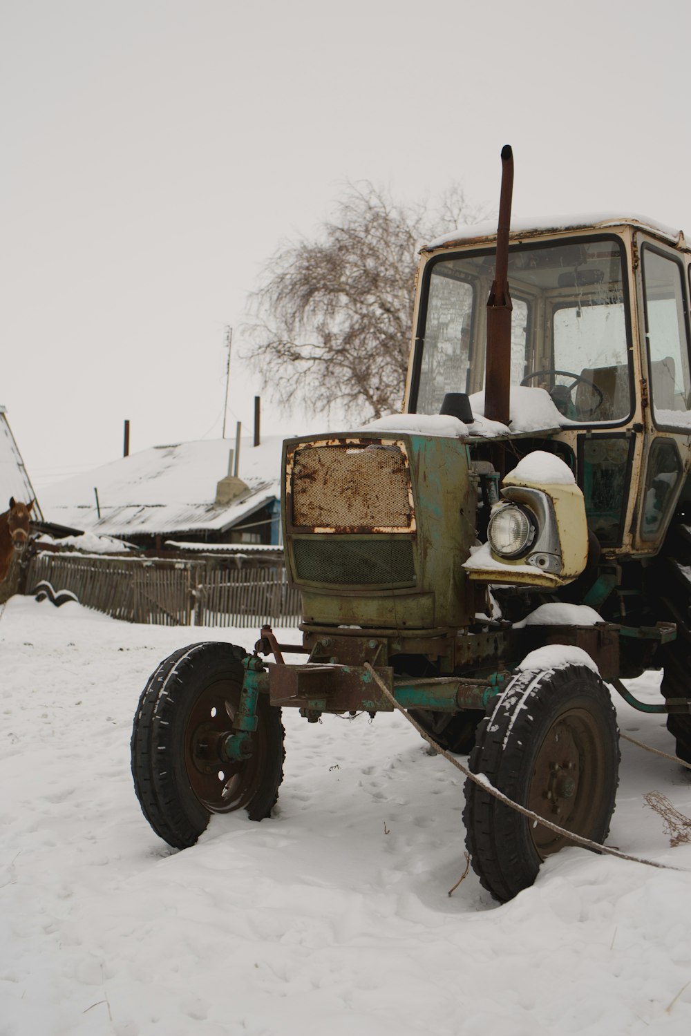 green and brown tractor on snow covered ground during daytime