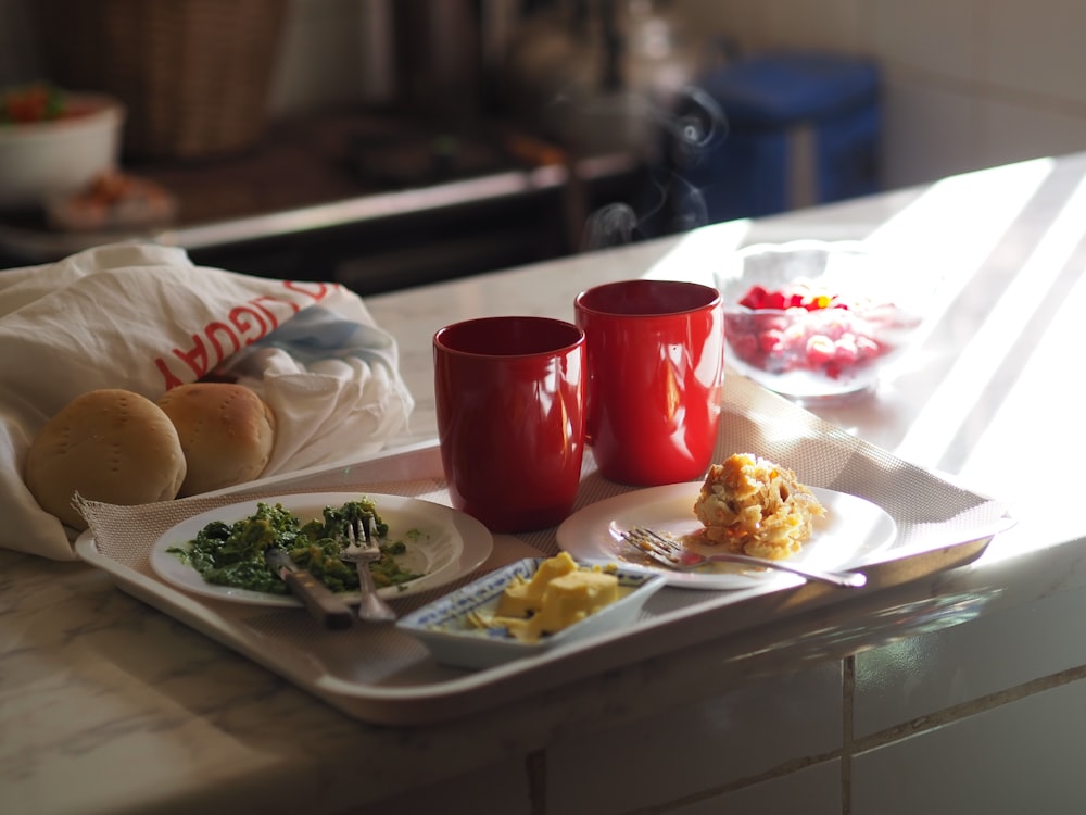 Tasse en céramique rouge à côté d’une assiette en céramique blanche sur la table