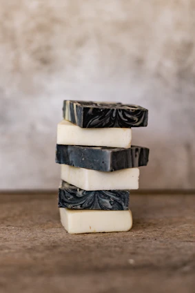 Close-up of artisan soaps arranged on a light wooden surface with soft natural lighting highlighting their textures and colors.
