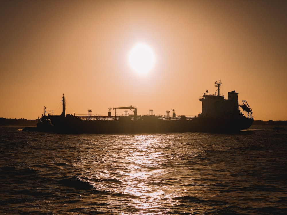 silhouette of ship on sea during sunset