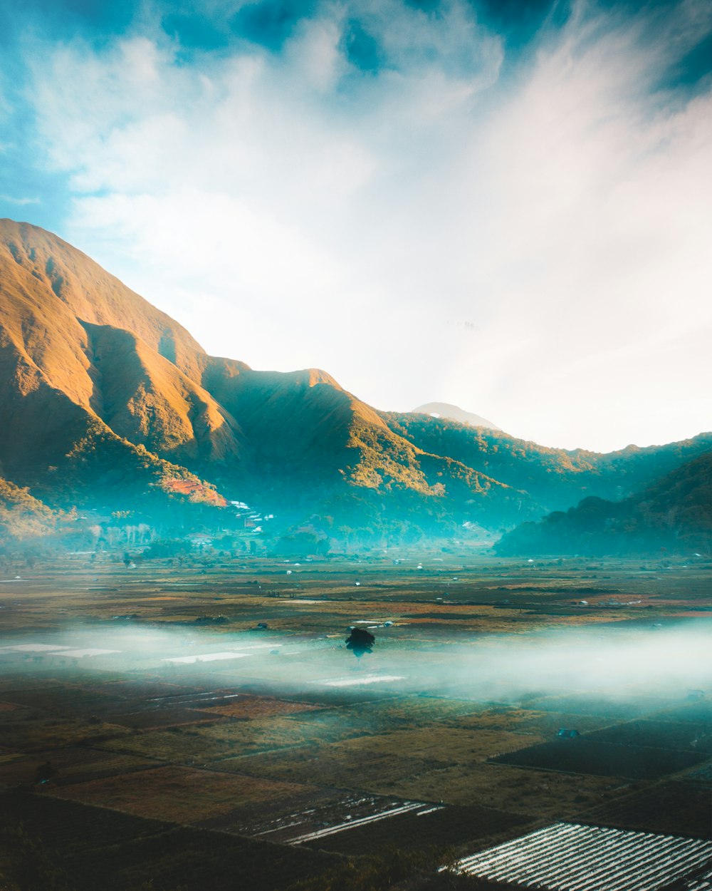 person surfing on sea near mountain during daytime