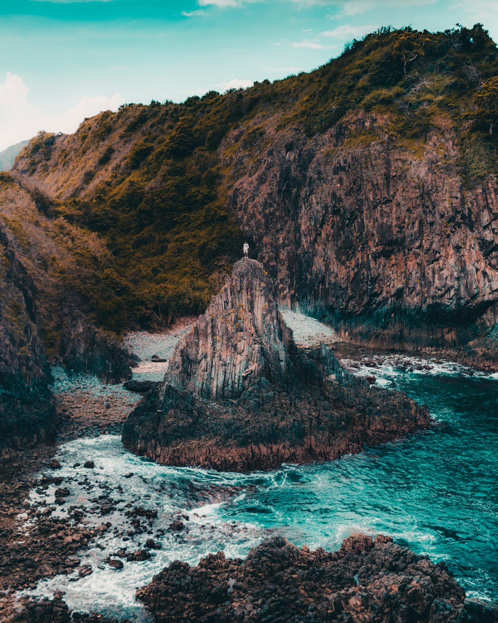 brown and green mountain beside body of water during daytime