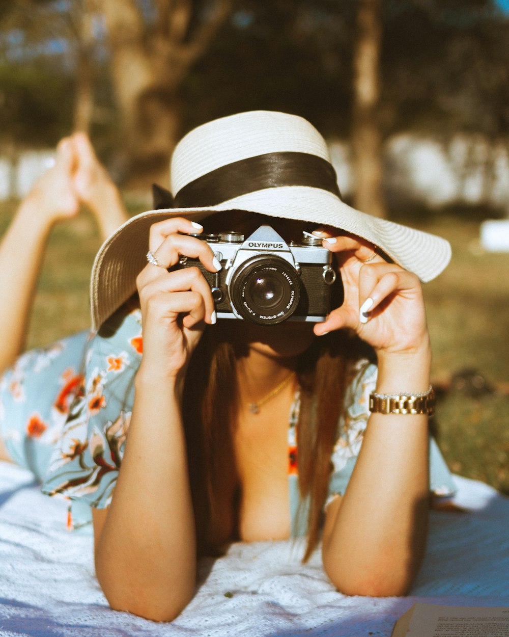 woman in white and blue floral shirt holding black and silver camera