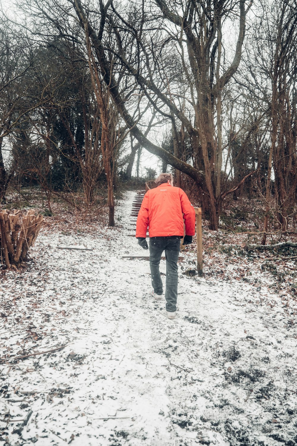 雪に覆われた地面に立つオレンジ色のジャケットを着た男性