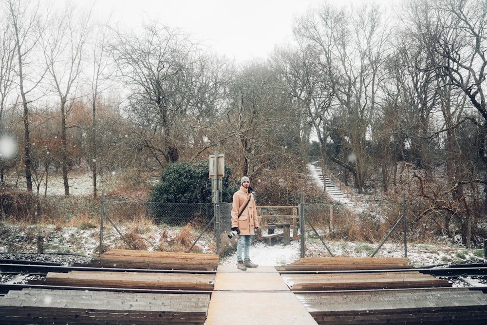 woman in white shirt and blue denim jeans walking on wooden bridge during daytime