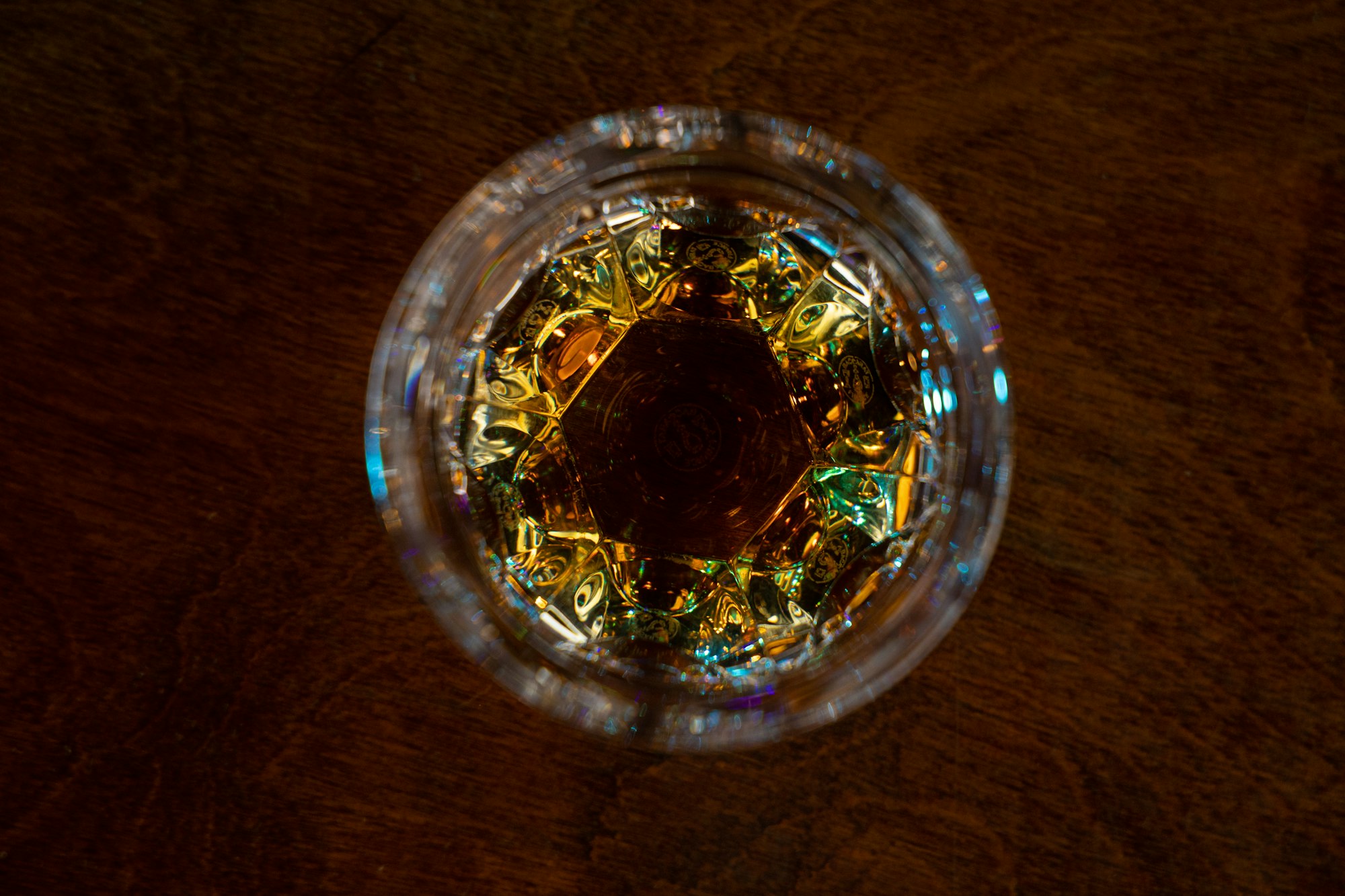 A top-down shot of a glass of whiskey sitting on a bar top. 