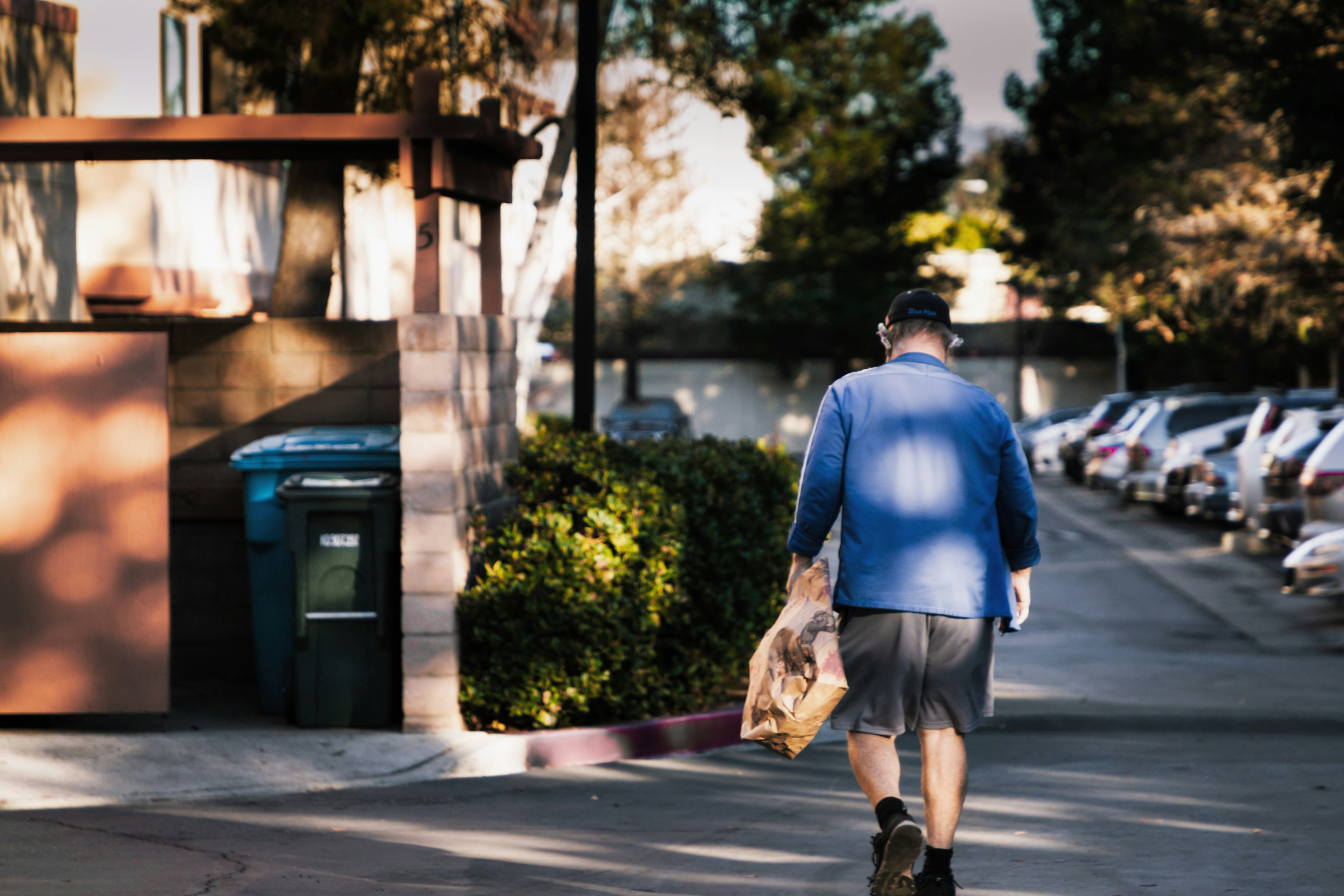 man in blue dress shirt and brown pants standing on sidewalk during daytime