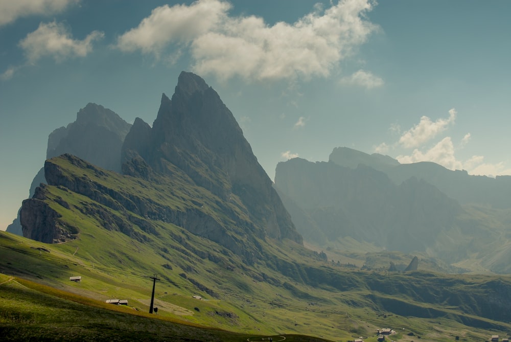 campo di erba verde vicino alla montagna sotto nuvole bianche durante il giorno