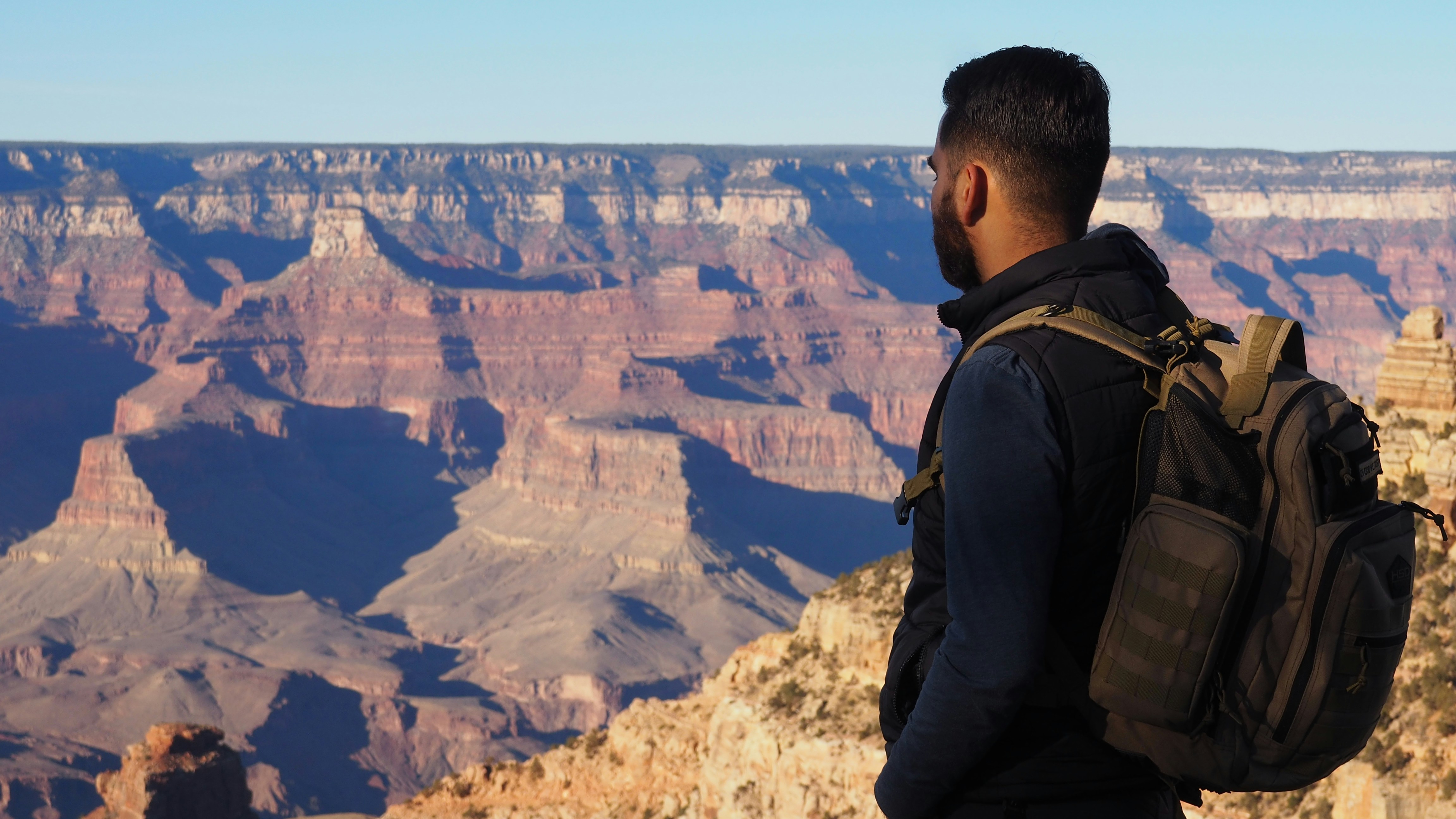 man in black jacket standing on top of mountain during daytime