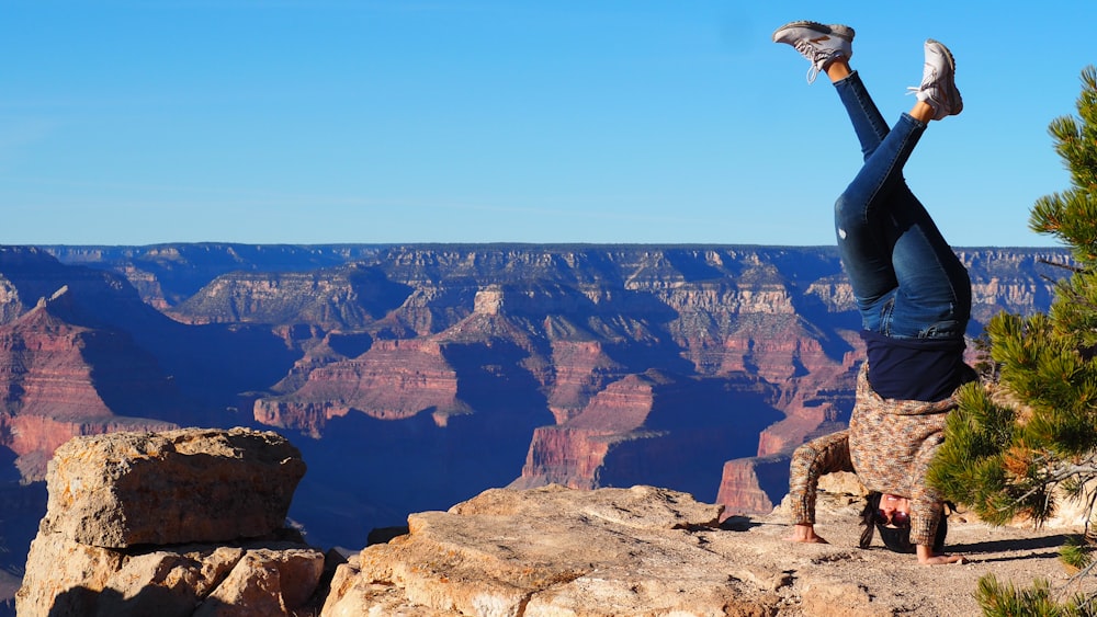 man in white shirt sitting on rock formation during daytime