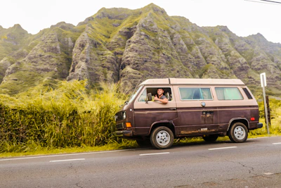 A friendly local driver-guide smiling next to a comfortable van ready for a road trip.