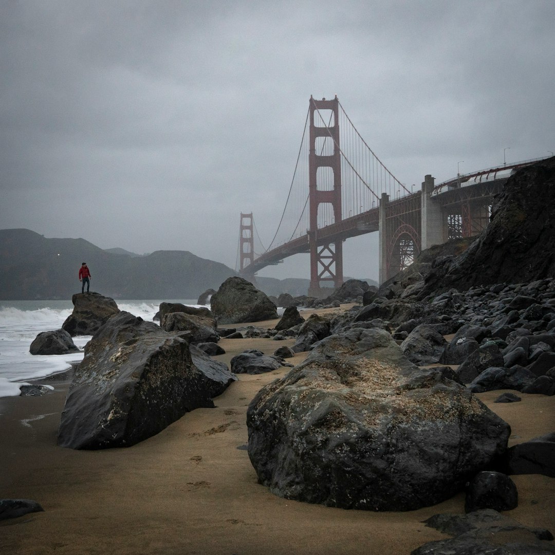 person sitting on rock near golden gate bridge during daytime