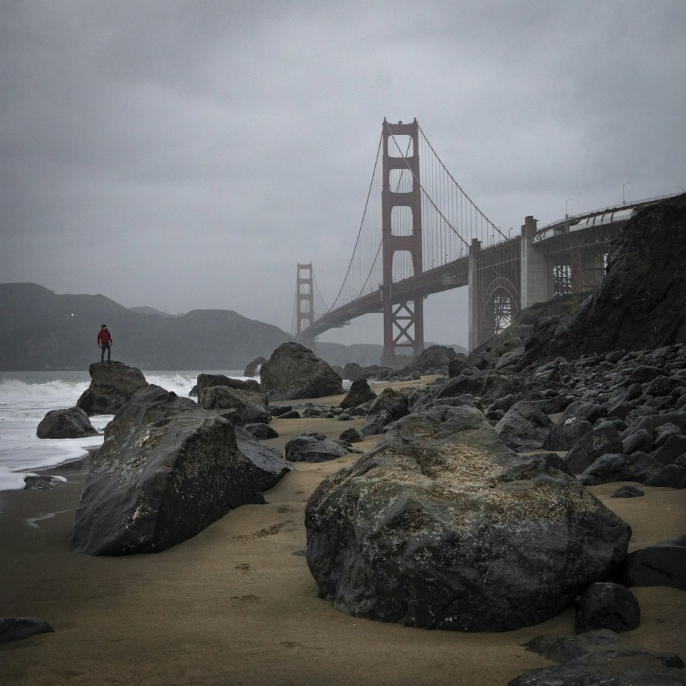 person sitting on rock near golden gate bridge during daytime