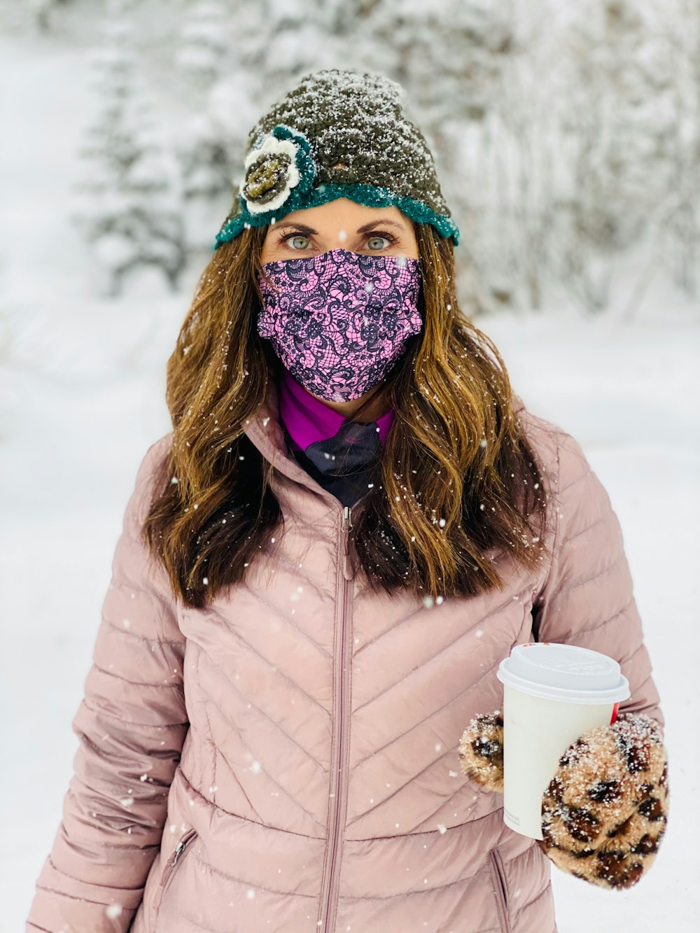 woman in white jacket wearing blue and white mask holding white disposable cup