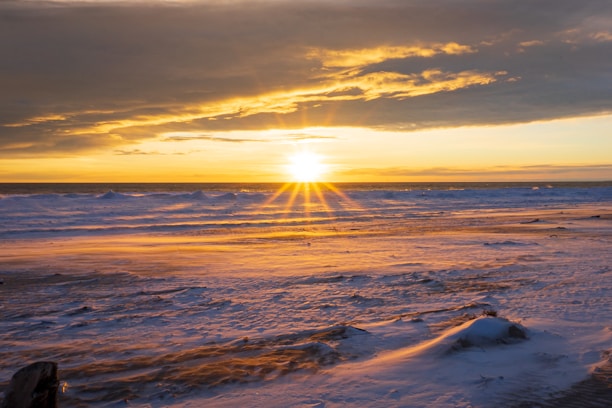 A golden sunrise illuminating a serene beachfront resort with crystal-clear waters.