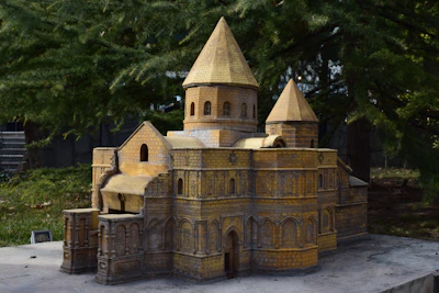 Hands building a small-scale breathable architectural model using natural materials.