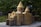 A detailed miniature model of a historic building with intricate architectural features, including stone-like texture, arches, and conical roofs. The model is set outdoors, surrounded by lush green foliage that provides a natural backdrop.