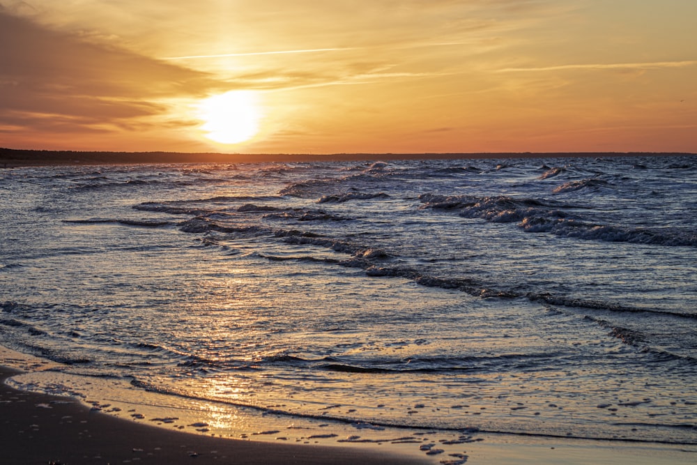 ocean waves crashing on shore during sunset